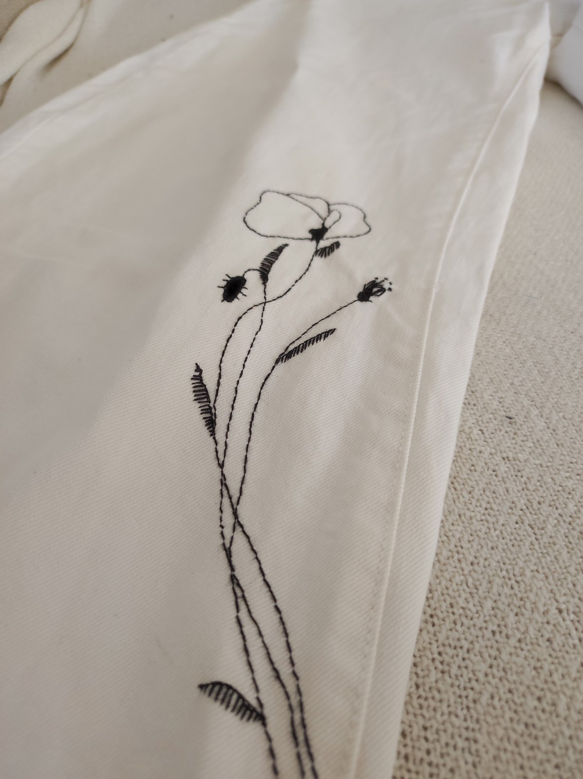 Black botanical linework placed on white denim